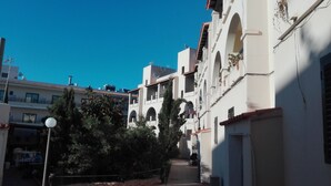 A narrow street with white buildings, arched windows, and a clear blue sky. - Es Pujol: Apartment/ flat - Es Pujol (Es Pujol)