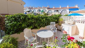 A patio with a round table and chairs, surrounded by potted plants and flowers. - CH Ronda Doña Pepa (Ciudad Quesada) (Ciudad Quesada)