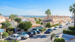 A residential street with parked cars, palm trees, and houses with a view of the sea. - CH Ronda Doña Pepa (Ciudad Quesada) (Ciudad Quesada)