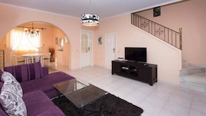 A living room with a sofa, TV, and a staircase. - CH Ronda Doña Pepa (Ciudad Quesada) (Ciudad Quesada)
