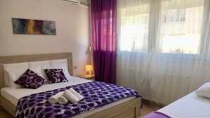 Ein Hotelzimmer mit Bett, Nachttisch, Lampe und einem Fenster mit Vorhängen.