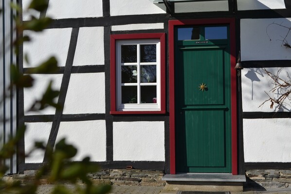 A traditional half-timbered building with a green door and a white-framed window.
