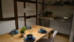 Uma sala de jantar com uma mesa de madeira posta para quatro pessoas, um micro-ondas e uma máquina de lavar louça ao fundo.