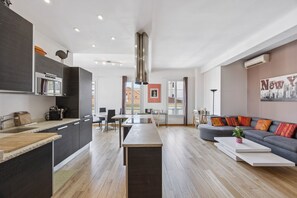 A modern living space with a kitchen, dining area, and a sofa with colorful cushions. - Happyfew la terrasse de Blacas (Nice)