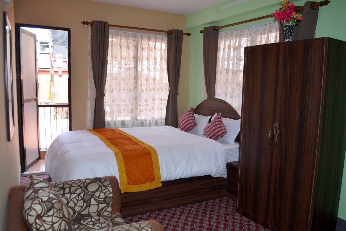 A bedroom with a bed, a wardrobe, and a window with curtains.