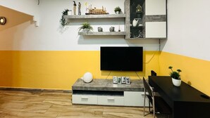 A modern living room with a flat-screen TV, a grey entertainment unit, and a dining area with a black table and chairs. - 4 mint to beach and 20 mint to las Ramblas plaza catalunya Barcelona  (San Adrián del Besós)