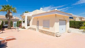 A single-story house with a small porch, a garage, and a palm tree in the background. - CH Isla Menorca Ciudad Quesada (Ciudad Quesada)