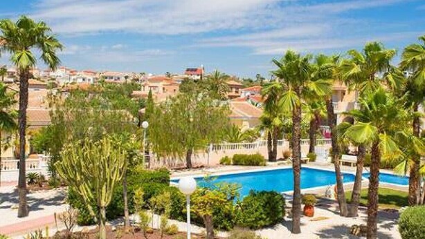 A pool surrounded by palm trees and a view of a residential area. - CH Isla Menorca Ciudad Quesada (Ciudad Quesada)