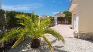 A courtyard with a palm tree, a pergola, and a building with a tiled floor. - CH Isla Menorca Ciudad Quesada (Ciudad Quesada)