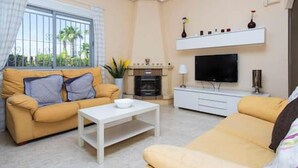 A living room with a sofa, a coffee table, a TV, and a fireplace. - CH Isla Menorca Ciudad Quesada (Ciudad Quesada)