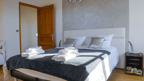 Een slaapkamer met een bed, kussens, een nachtkastje en een deur.