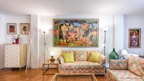 Een woonkamer met een bank, salontafel, lamp, vloerlamp en een schilderij aan de muur.