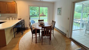 Una cocina con armarios de madera, encimera blanca y comedor con mesa redonda y sillas.