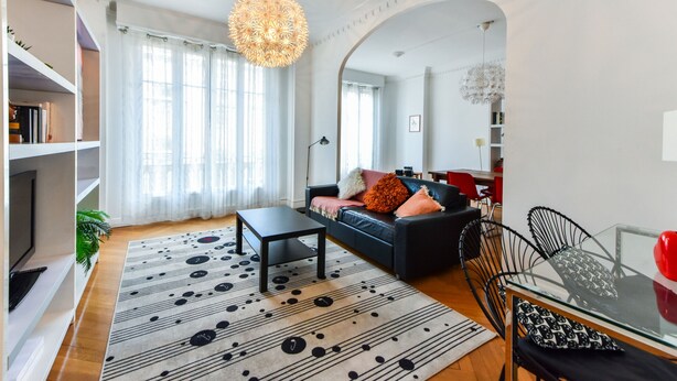 Una sala moderna con un sofá, una mesa de centro y un comedor con sillas y una mesa de vidrio.