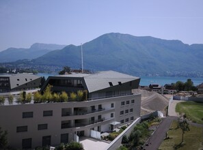 A modern building with a flat roof and multiple balconies, surrounded by greenery and a mountainous backdrop. - 🎖Le Répertoire du Lac - Appartment 1 bedroom for 2 or 4 people + garage (Annecy)