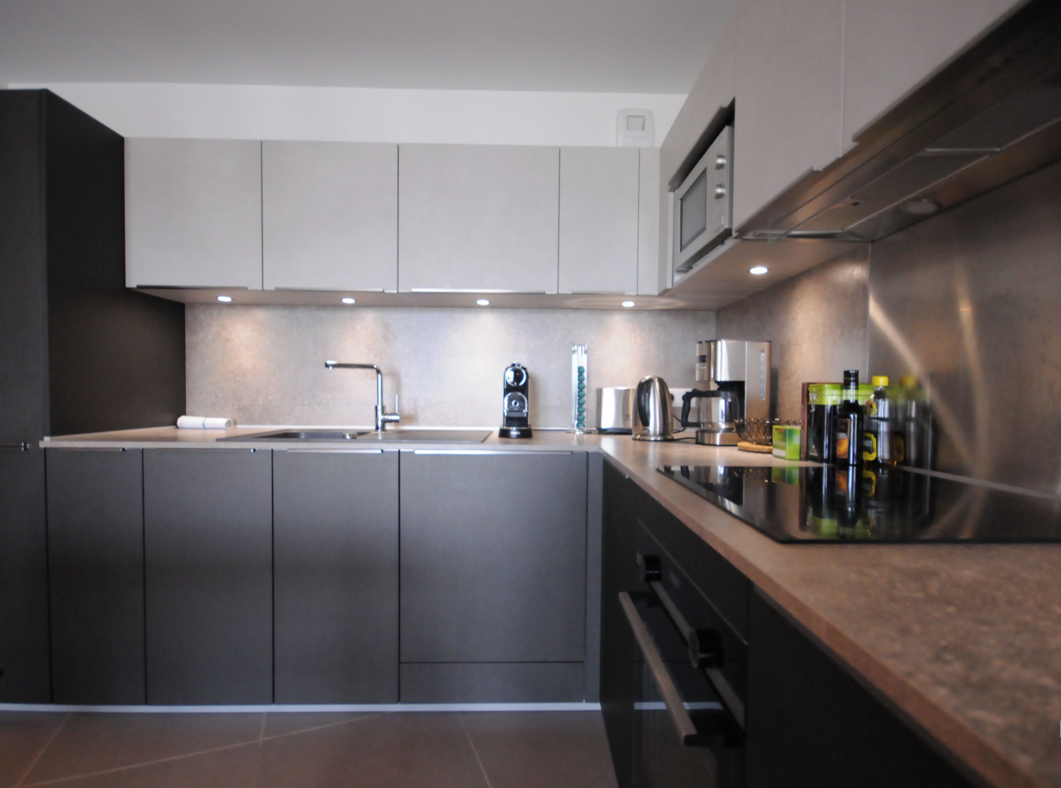 A modern kitchen with a central island, stainless steel appliances, and a sleek countertop.