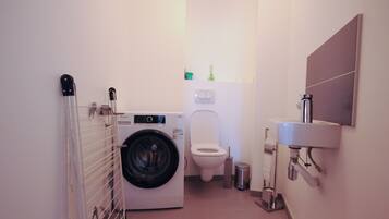 Een kleine badkamer met een wasmachine, toilet en wastafel.
