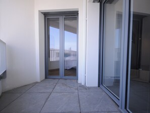 Un balcón con puerta corredera de vidrio que da a una terraza.