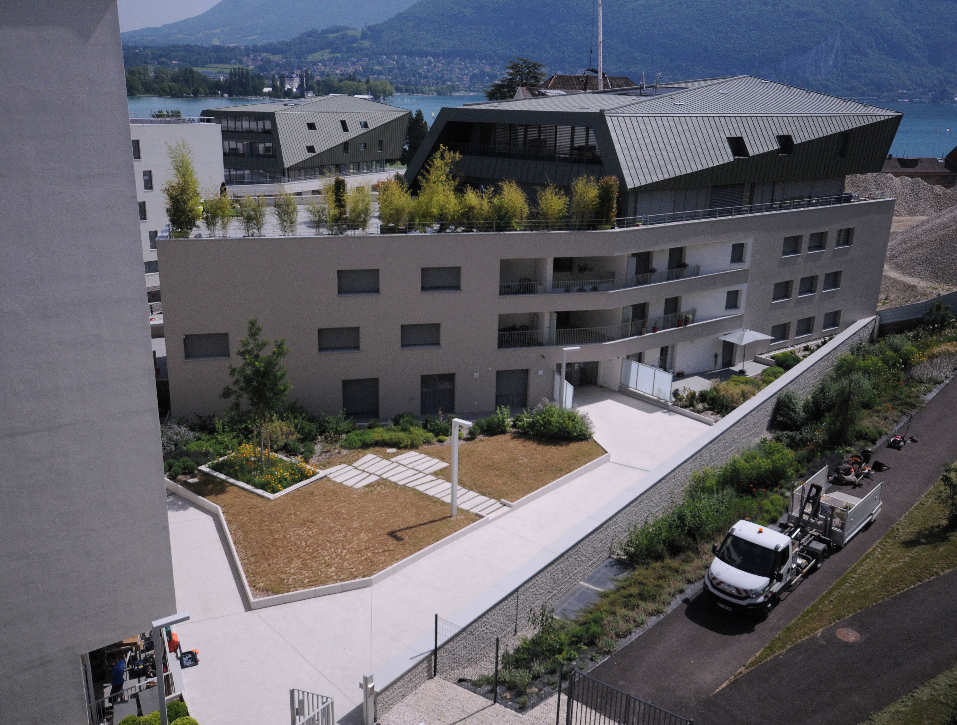 A modern building with a flat roof, multiple balconies, and a landscaped courtyard.