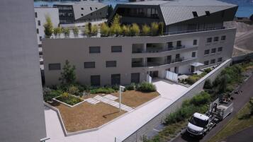 A modern building with a flat roof, multiple balconies, and a landscaped courtyard.