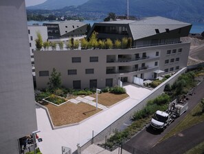 Un edificio moderno con tejado plano, varios balcones y un patio ajardinado.
