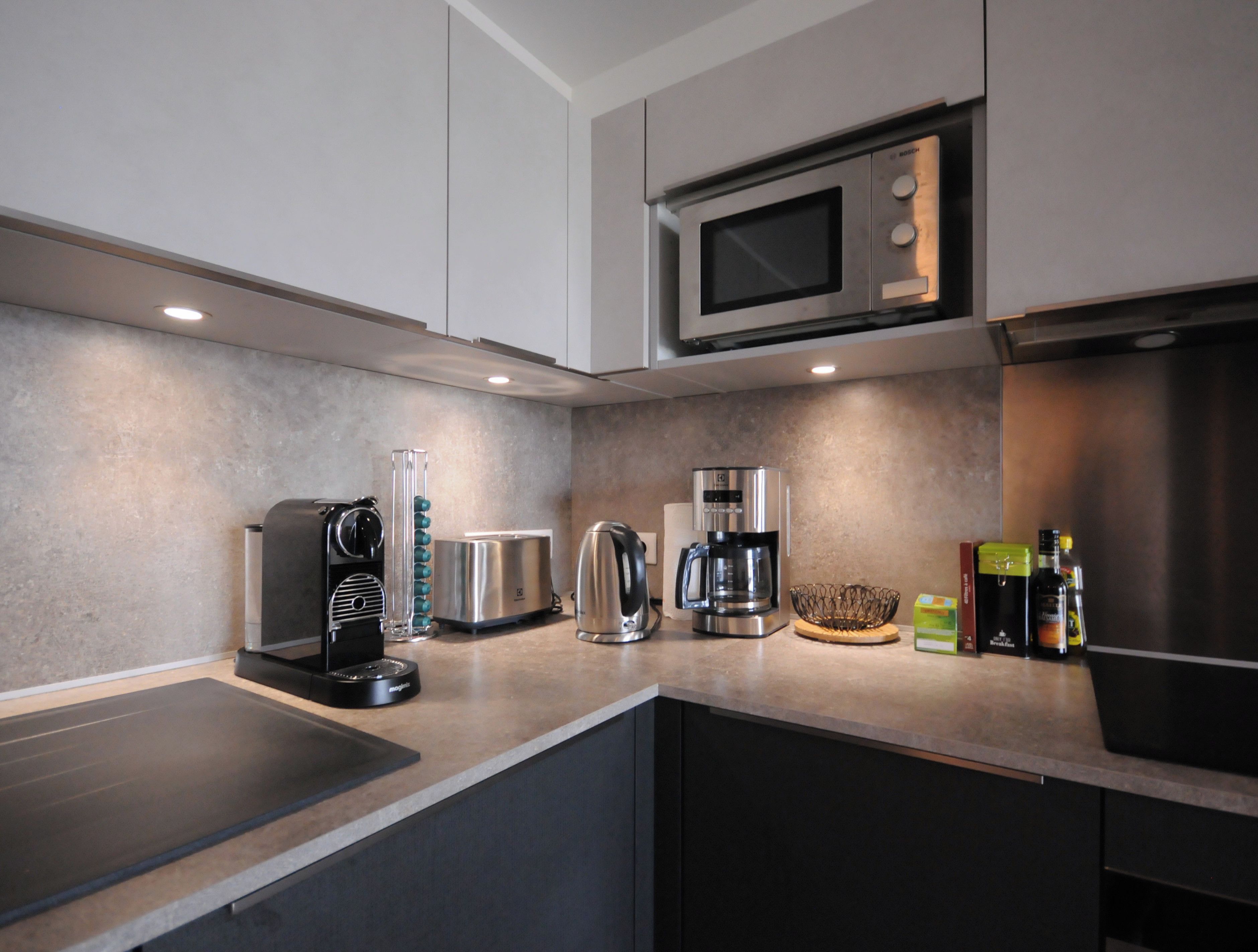 A modern kitchen with a microwave, toaster, coffee maker, and various appliances.