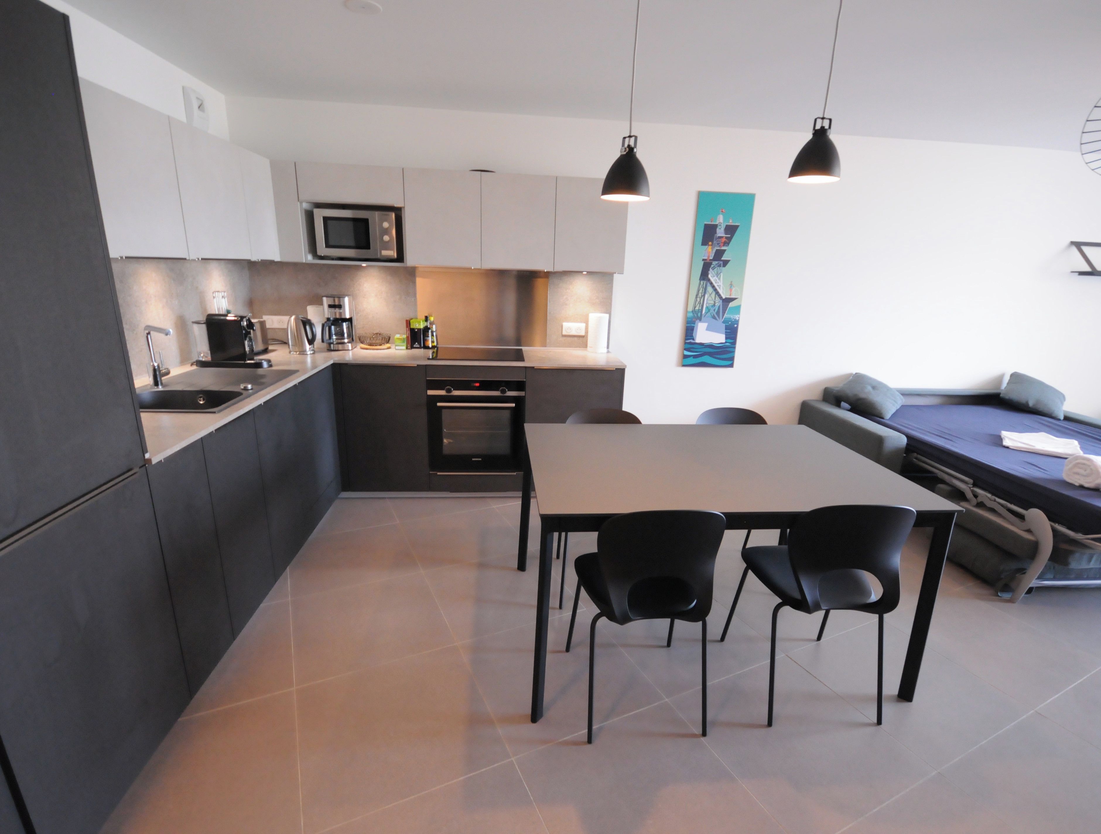 A modern kitchen with a dining area, a microwave, a coffee maker, and a painting on the wall.