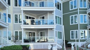 A multi-story waterfront hotel with balconies, a wooden deck, and a dock. - Chincoteague Getaway on the Bay - Water Front,Pool ,IN TOWN ,LINENS & TOWELS (Chincoteague)