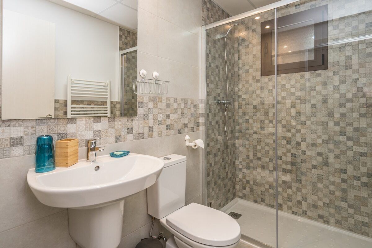 Un baño con lavabo, inodoro y ducha con mampara de vidrio.