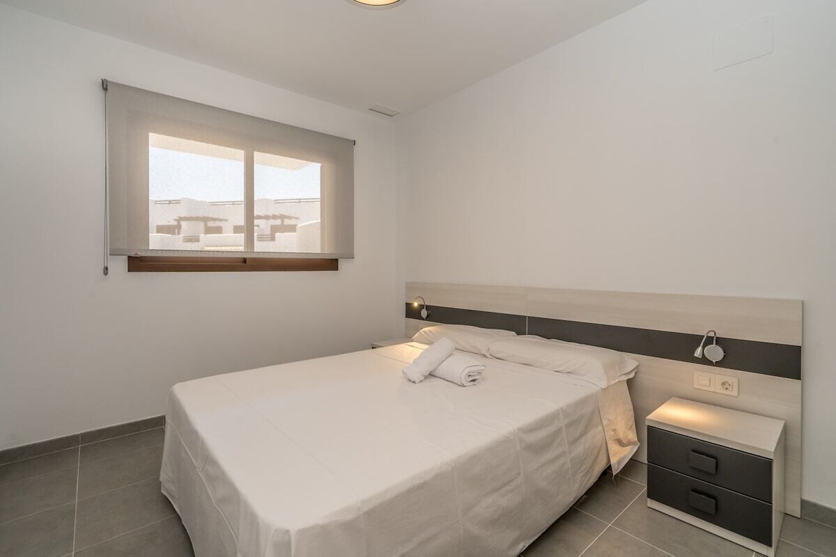 A bedroom with a bed, bedside tables, and a window.