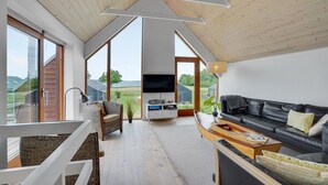 A spacious living area with a large black leather sofa, a television, and a wooden dining table. - Nice home in Stubbekøbing with WiFi (Stubbekøbing)