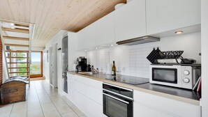 A modern kitchen with white cabinetry, a built-in oven, a microwave, and a coffee maker. - Nice home in Stubbekøbing with WiFi (Stubbekøbing)