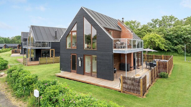 A modern two-story house with a large deck, a balcony, and a fenced garden area. - Nice home in Stubbekøbing with WiFi (Stubbekøbing)