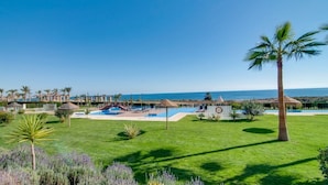 Un complexe hôtelier doté d’une piscine, de palmiers et offrant une vue sur la mer.