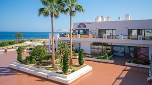 Un hôtel avec vue sur la plage, des palmiers et des espaces de détente en plein air.
