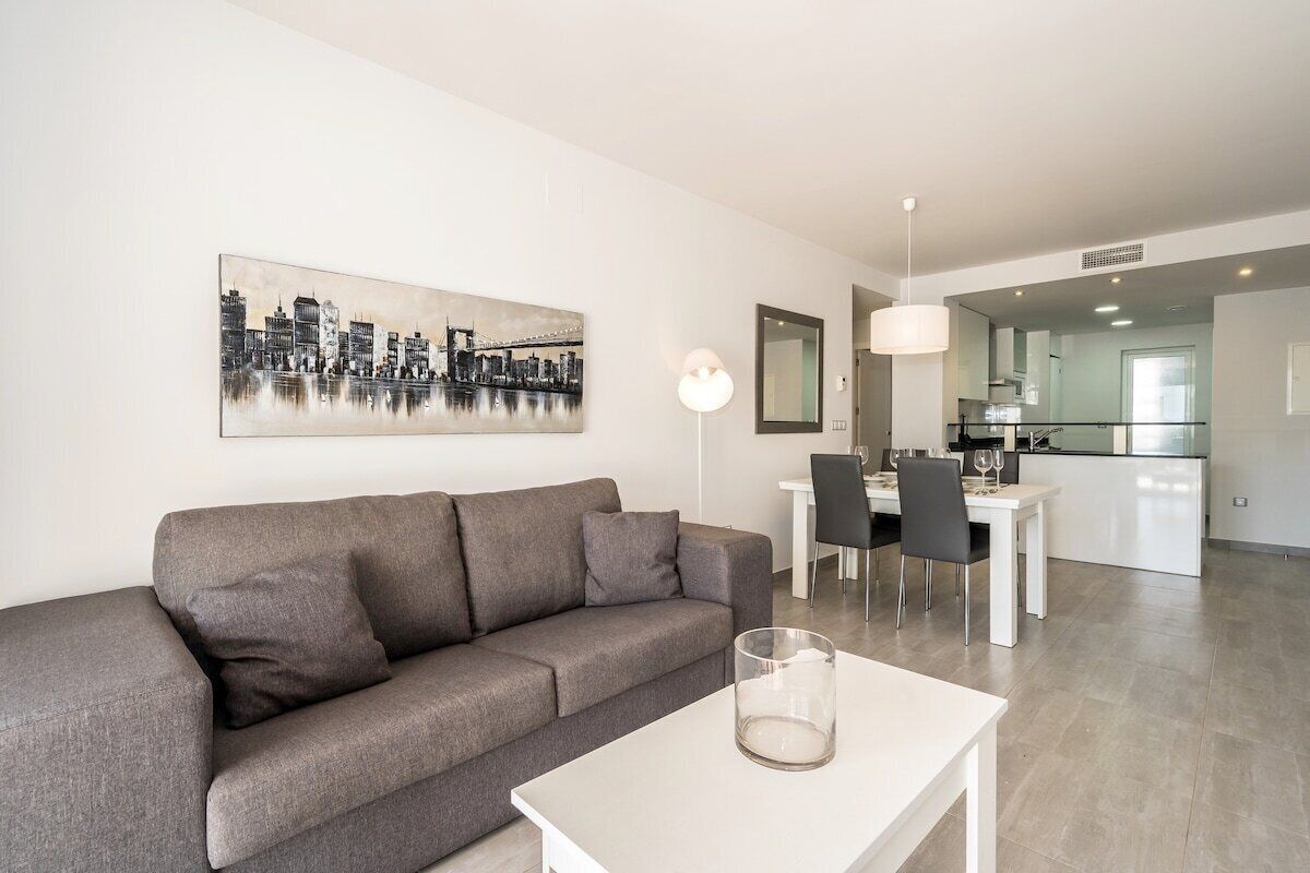 A modern living room with a grey sofa, a white coffee table, and a cityscape painting on the wall.