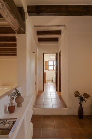 A narrow hallway with white walls and wooden beams, leading to a room with a window and a door. - Villa with terrace and BBQ equipped with all amenities (Sant Francesc de Formentera)