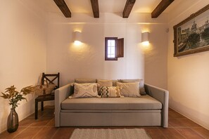 A cozy living room with a sofa, a chair, a small window, and a painting on the wall. - Villa with terrace and BBQ equipped with all amenities (Sant Francesc de Formentera)