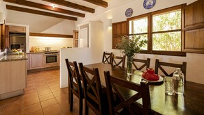 Une cuisine avec des poutres en bois, une table à manger avec des chaises et une fenêtre donnant sur un paysage verdoyant.