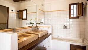 Une salle de bain avec deux lavabos, une baignoire et un grand miroir.