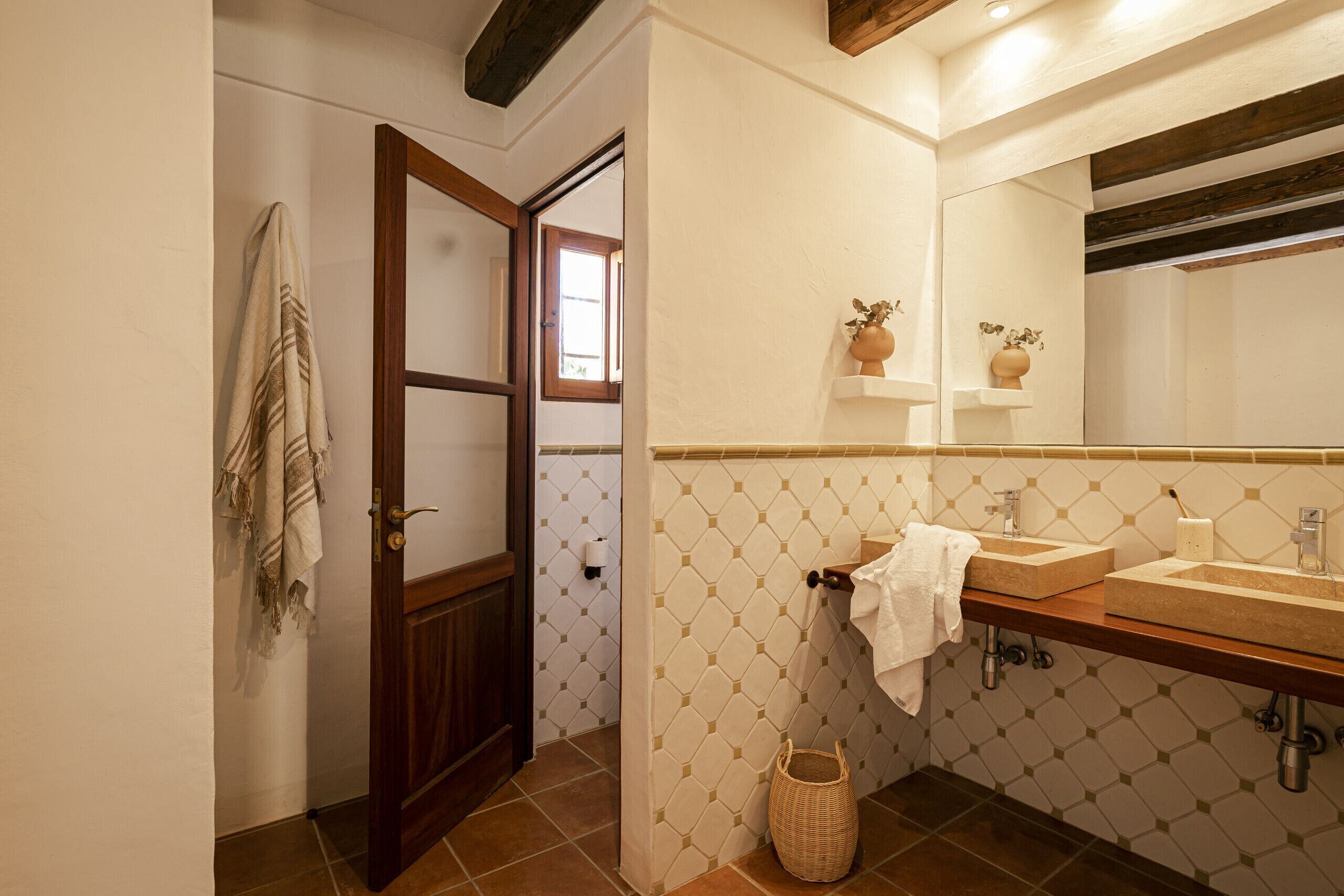 Un baño con dos lavamanos, un espejo grande y una puerta de madera.