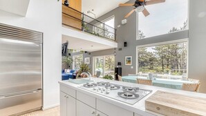 A modern kitchen with a stainless steel refrigerator, a gas stove, and a wooden countertop. - Dunes Summer Retreat • Easy Walk to Private Ocean Beach (Amagansett)