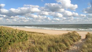 A beach with a sandy shore and grassy dunes. - Dunes Summer Retreat • Easy Walk to Private Ocean Beach (Amagansett)