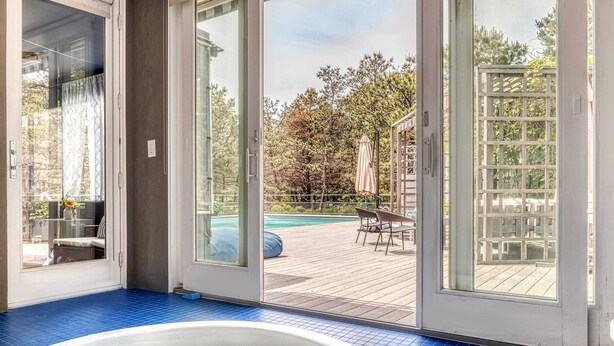 A hot tub in a room with a view of a wooden deck and a pool. - Dunes Summer Retreat • Easy Walk to Private Ocean Beach (Amagansett)