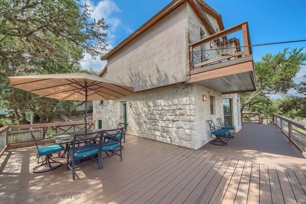 A stone building with a wooden deck, outdoor seating, and a balcony.