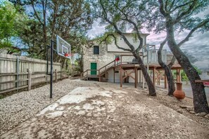 A stone building with a basketball court, a wooden deck, and a staircase leading to a second level.
