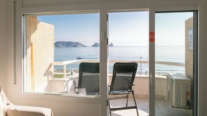En balkon med to stole, havudsigt og en bygning med et rødt skilt.