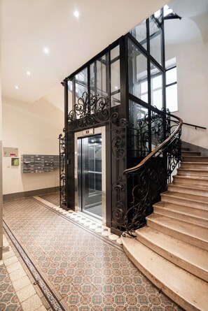 A staircase with ornate black metal railings and a patterned floor.