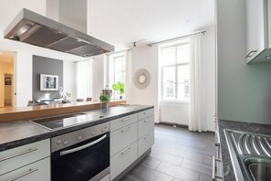 A modern kitchen with a large island, built-in oven, and stainless steel appliances.