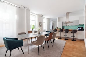 A modern kitchen with a green backsplash, a dining area with a round table and chairs, and a bar area with stools.